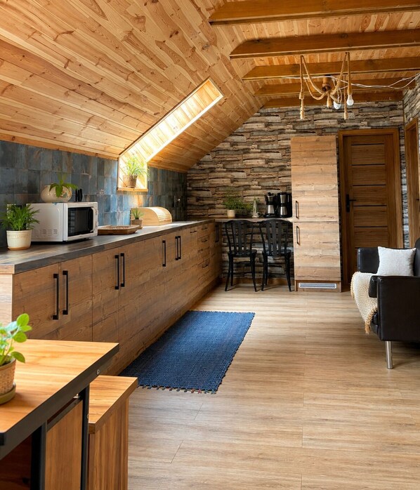 Una cocina moderna con armarios de madera, un microondas y una pared de piedra.