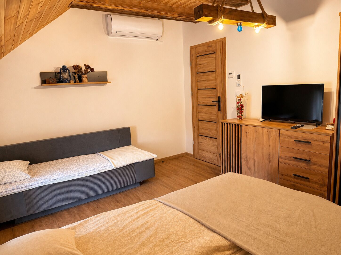 A bedroom with a bed, a TV, a wardrobe, and a shelf with decorative items.