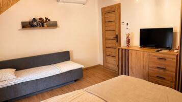 A bedroom with a bed, a TV, a wardrobe, and a shelf with decorative items.