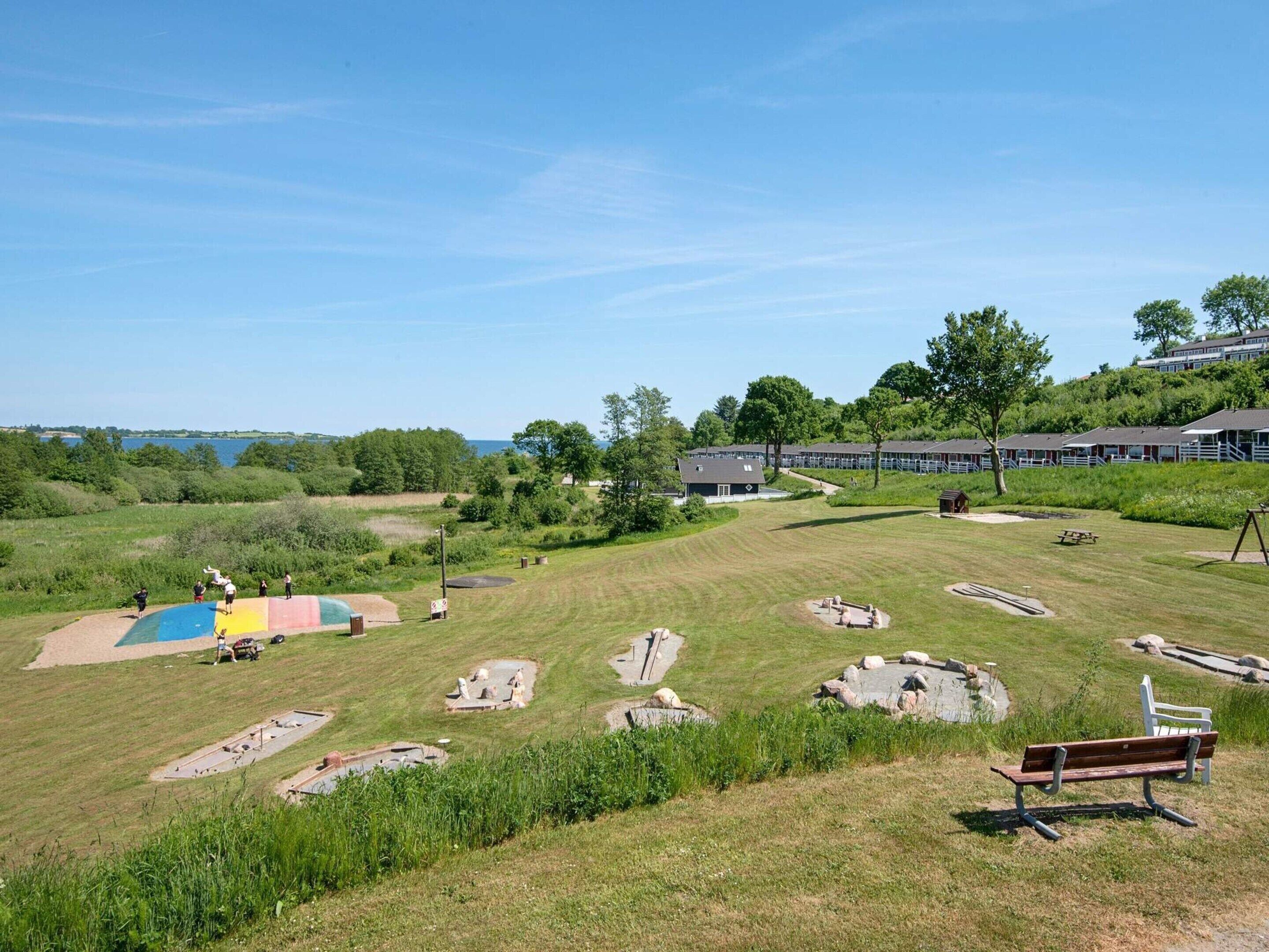 A grassy area with a playground, picnic tables, and a bench.