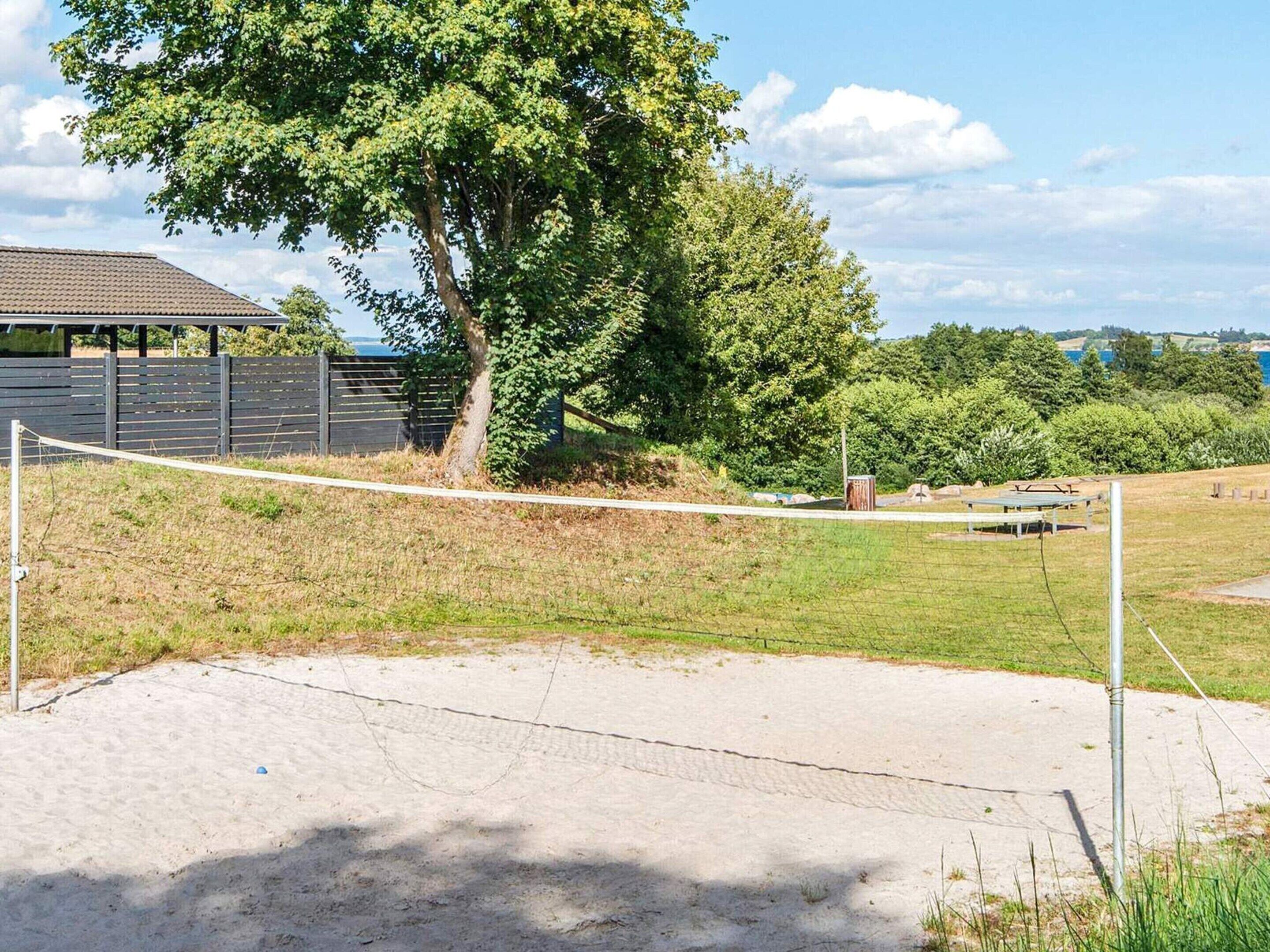A volleyball net in a grassy area with trees and a building in the background.