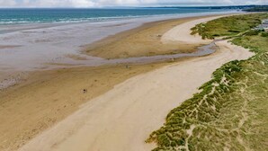 A beach with a sandy shore, a grassy area, and a clear sky. - Seagull Shack (Porthmadog)
