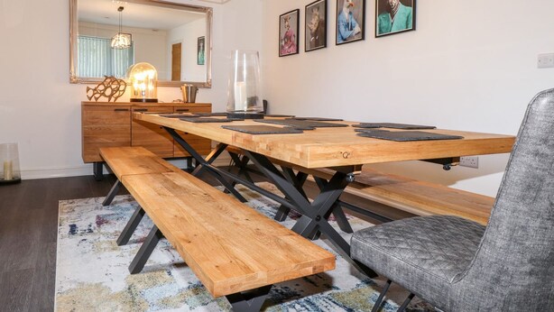 A dining area with a wooden table, benches, and a gray chair. - Seagull Shack (Porthmadog)