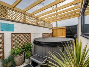 Ein Bereich mit Whirlpool, Holz-Pergola, Topfpflanzen und einem Schild mit Regeln.