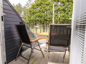 A patio with two chairs, a table, and a view of a forested area. - Seagull Shack (Porthmadog)