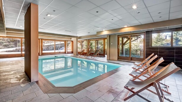A swimming pool with lounge chairs, large windows, and a tiled floor. - 6-guest Apartment With Alpine Views (Morillon)