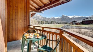 A wooden balcony with a table set for breakfast, overlooking snow-capped mountains. - 6-guest Apartment With Alpine Views (Morillon)