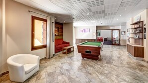 A billiards table, a red sofa, a white armchair, and a reception desk with shelves. - 6-guest Apartment With Alpine Views (Morillon)