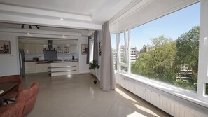 Eine moderne Wohnung mit Küche, Essbereich und großen Fenstern mit Blick auf die Stadt.