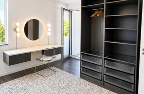 A modern vanity with a mirror and lights, a bench, and a walk-in closet with shelves.
