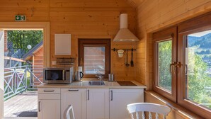 Une cuisine rustique aménagée dans une cabane en bois, avec un four à micro-ondes, une bouilloire et des ustensiles de cuisine accrochés au mur.