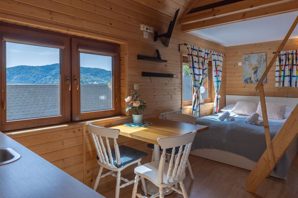 A wooden cabin with a dining area, a bed, and a view of the mountains.