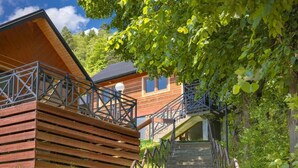 Une cabane en bois avec un escalier menant à une terrasse, le tout entouré d’une végétation luxuriante.