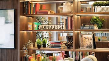 A bookshelf with a variety of books, a sign reading 'EDINBURGH,' and decorative items including plants and vases.