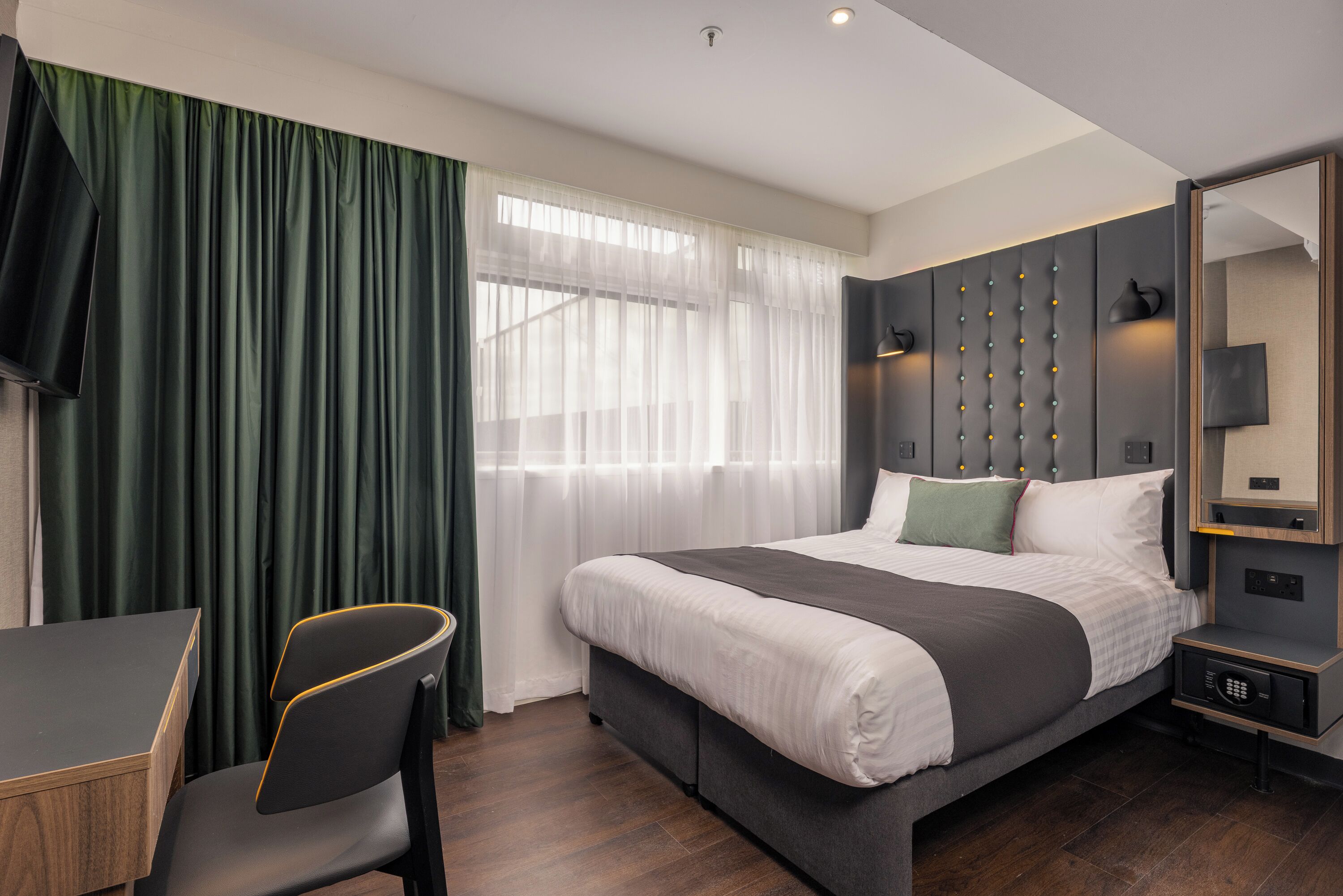 Una habitación de hotel moderna con una cama grande, un escritorio y una silla.