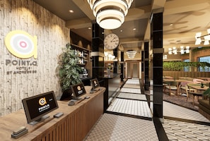 A hotel reception area with a wooden reception desk, a clock, and a seating area with tables and chairs. - Point A Edinburgh St Andrew Square (Edinburgh)