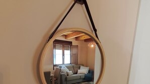 Een ronde spiegel met houten lijst hangt aan een muur.