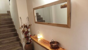 Een houten bank met een lantaarn en een schaal, een spiegel aan de muur, en een trap met houten treden.