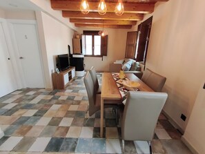 Un espace repas avec un sol à carreaux, des meubles en bois et des luminaires suspendus.