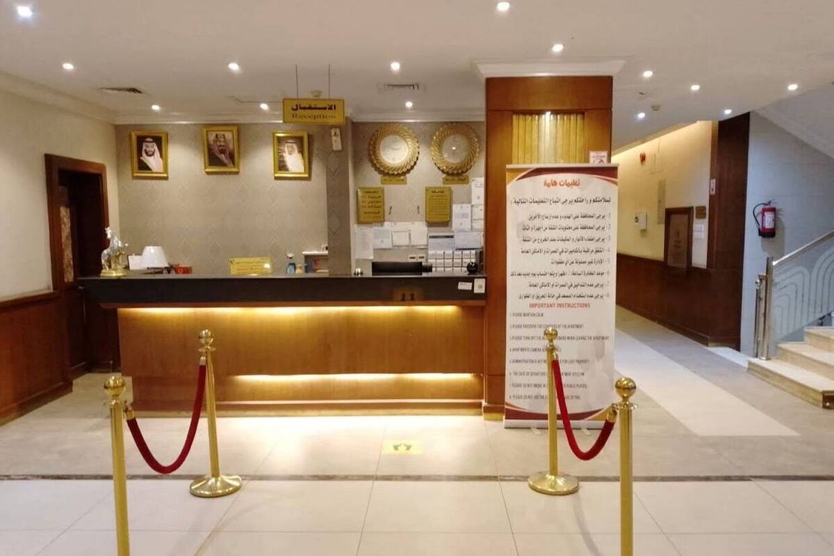 A reception area with a counter, framed pictures on the wall, a sign with instructions, and a red carpet leading to the entrance.