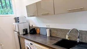 A compact kitchen with a washing machine, a coffee maker, a toaster, and a sink. - Garden apartment in the countryside near the sea pets welcome (Les Adrets-de-l'Estérel)