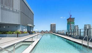 Ein Pool auf dem Dach mit Blick auf die Skyline der Stadt, darunter ein im Bau befindliches Gebäude.