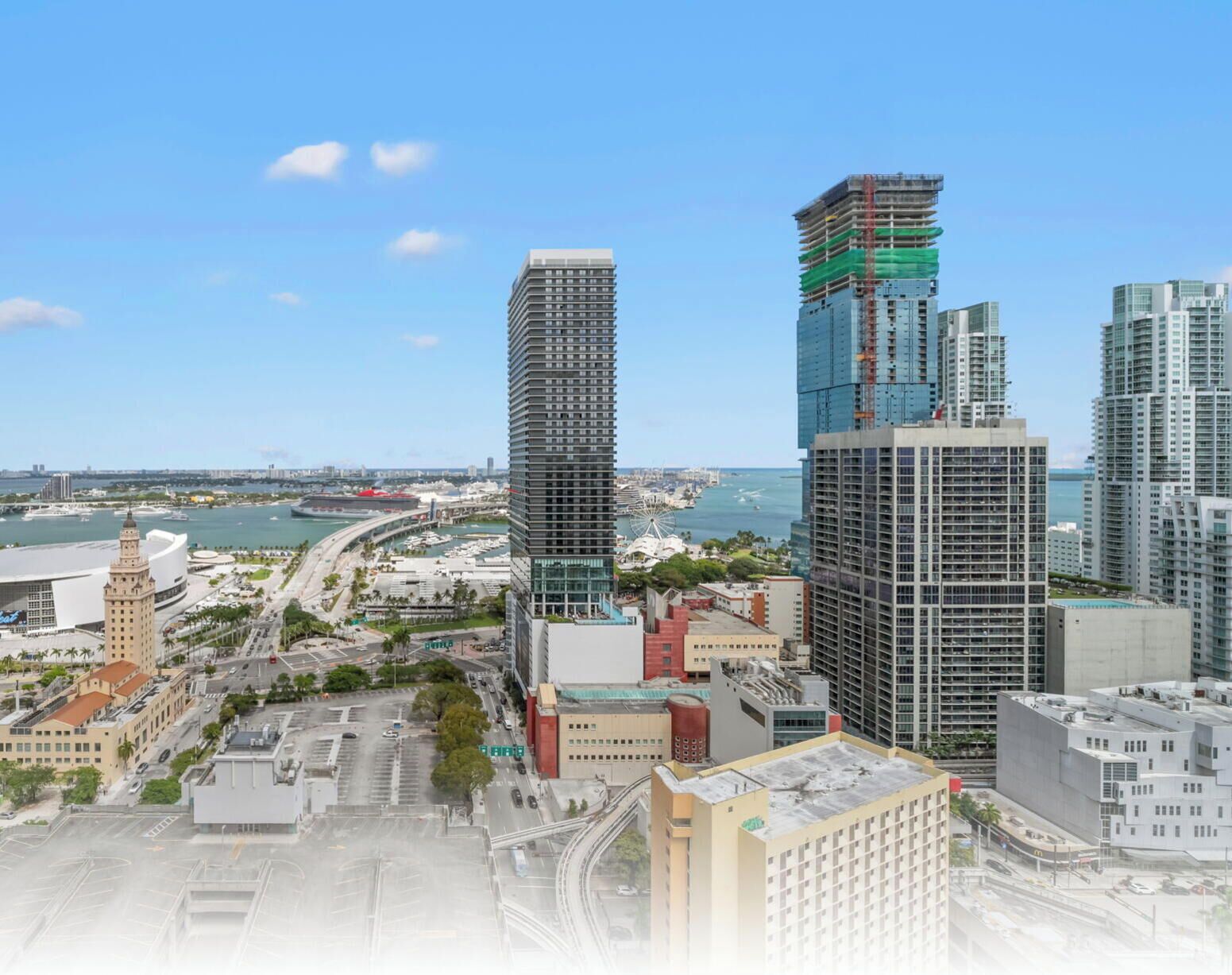 A cityscape with modern high-rise buildings, a waterfront, and a historic building with a clock tower.
