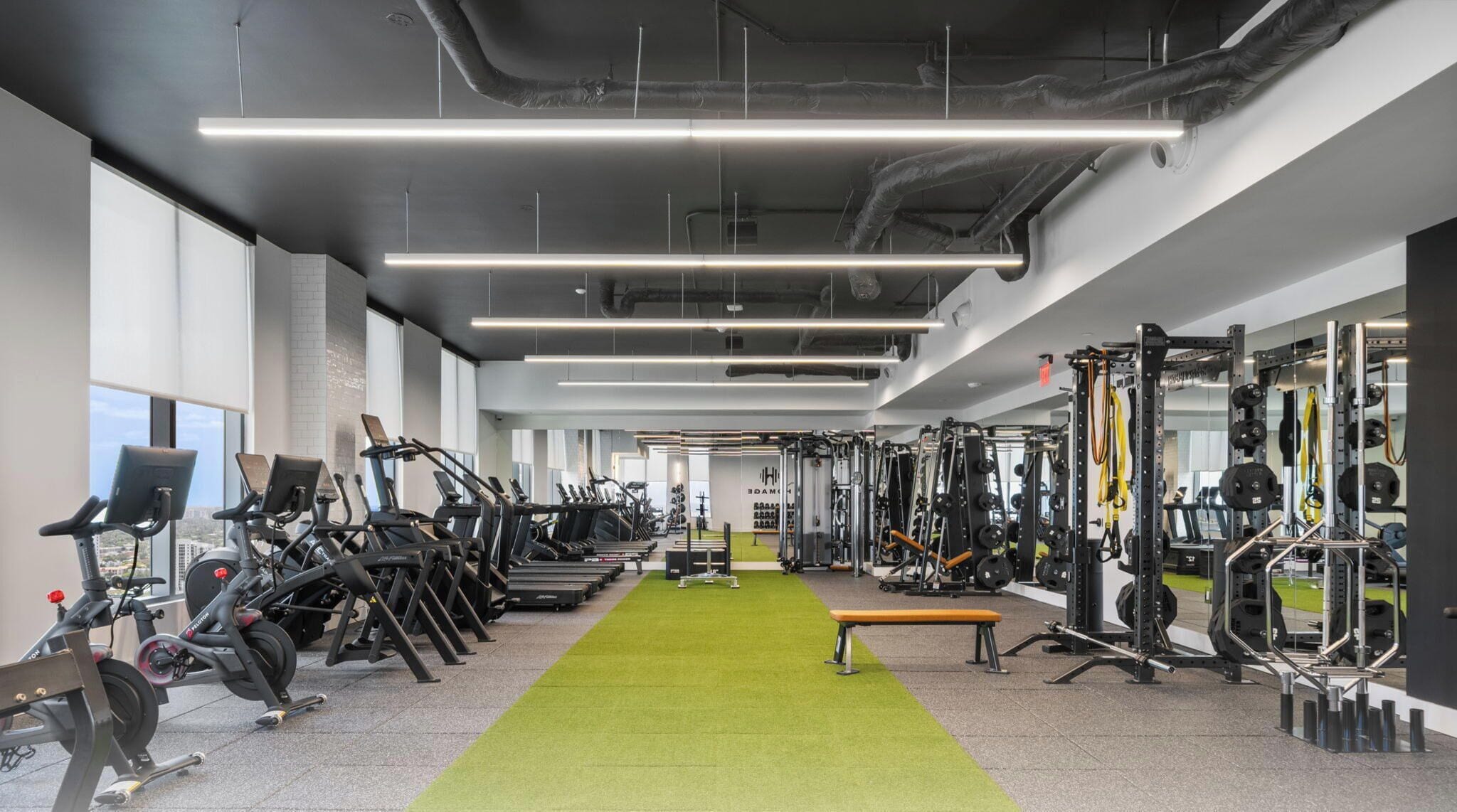 A gym with treadmills, weight machines, and a green carpet.