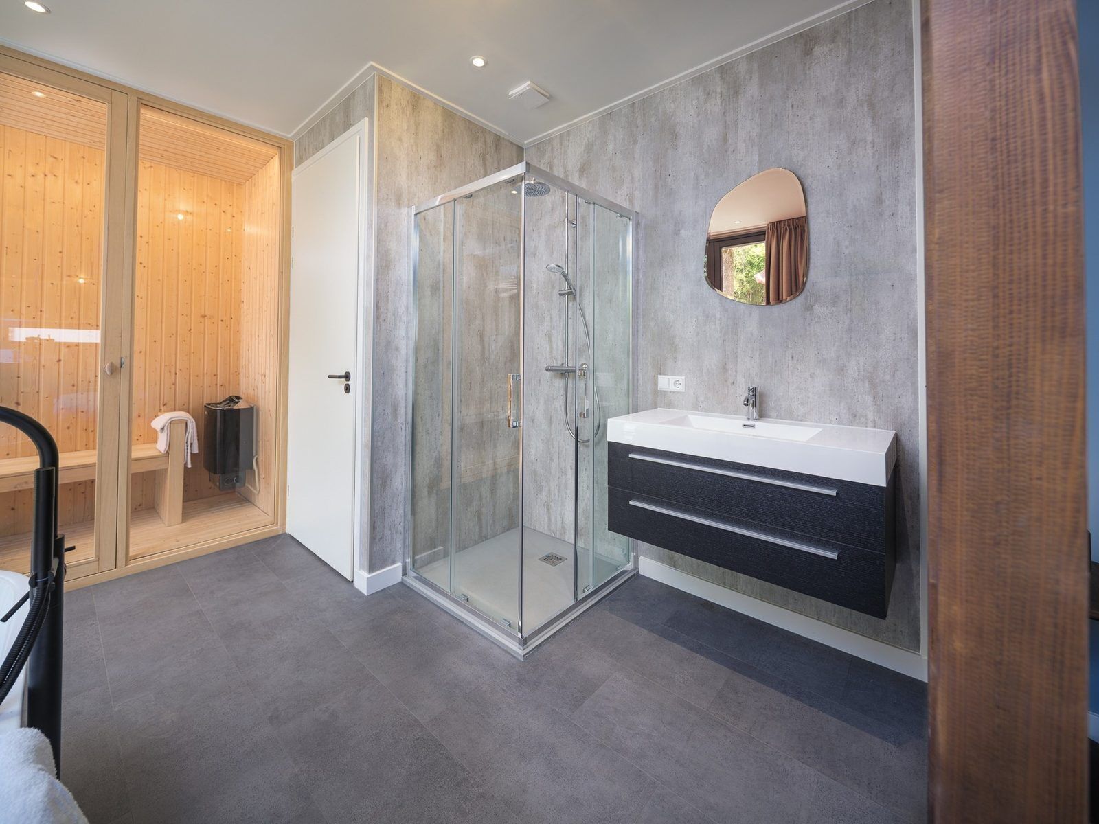 Une salle de bain moderne avec une douche à parois de verre, un meuble-lavabo avec un miroir et une porte en bois.