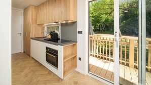 A modern kitchen with a built-in oven, a black stovetop, and a window overlooking a deck.