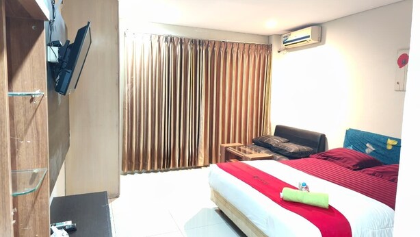 A hotel room with a bed, a desk, a chair, a TV mounted on the wall, and a window with curtains. - Hotel O near Balikpapan International Airport formerly Barkah Guest House (Balikpapan)