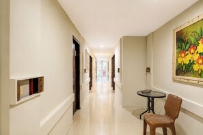 Um corredor com portas, uma pequena mesa e uma cadeira.