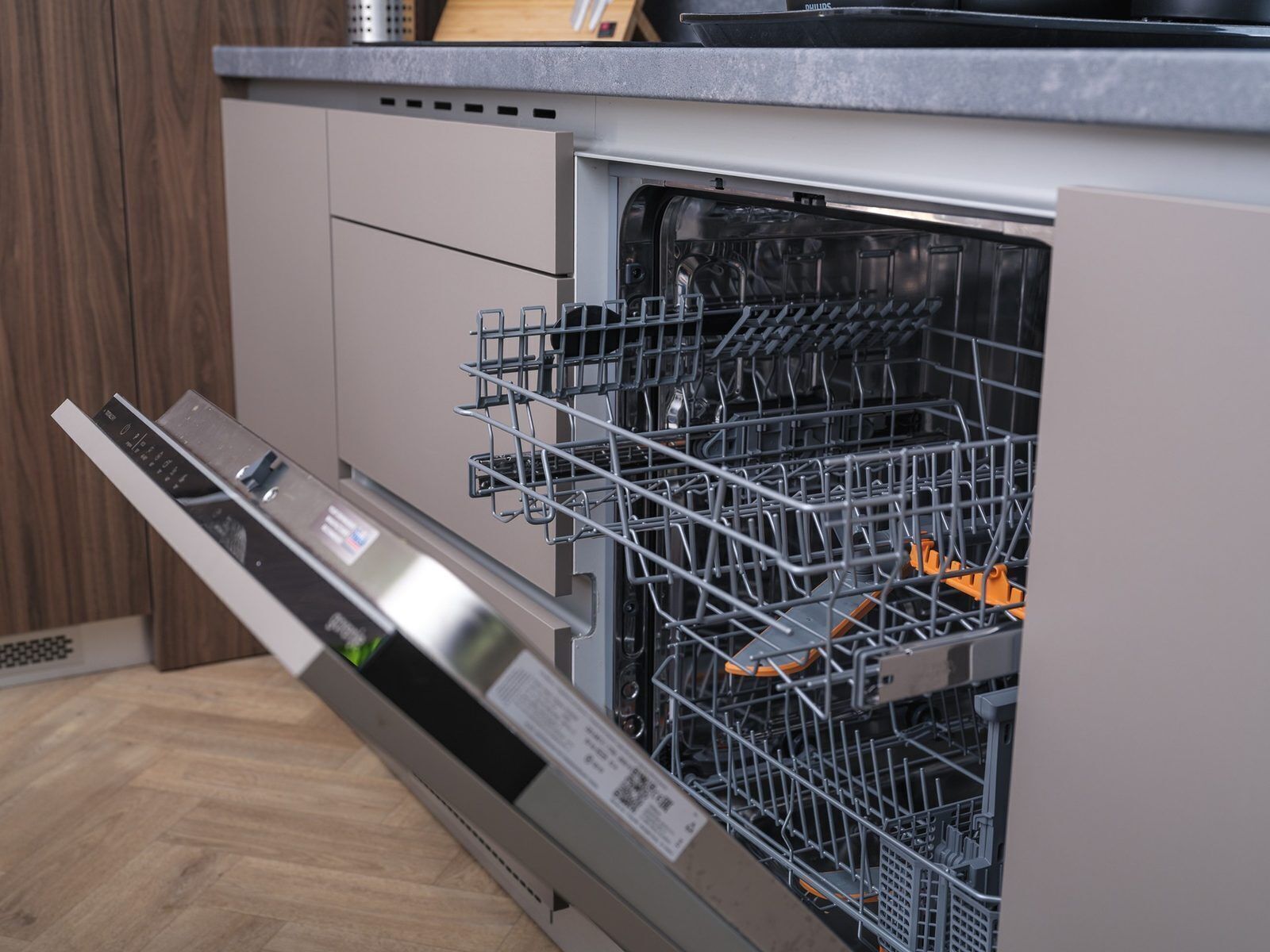 An open dishwasher with a control panel and a metal rack inside.