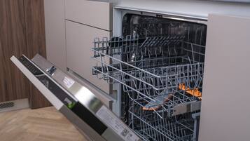 An open dishwasher with a control panel and a metal rack inside.