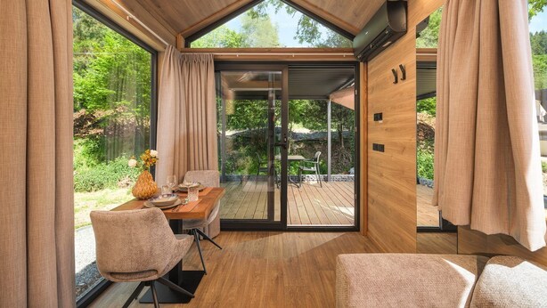 Un intérieur moderne comprenant un coin repas, un plancher en bois et de grandes fenêtres.