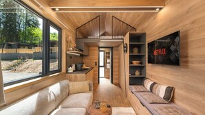 Un espace de vie compact comprenant un canapé, une petite table, une bibliothèque et un téléviseur fixé au mur.