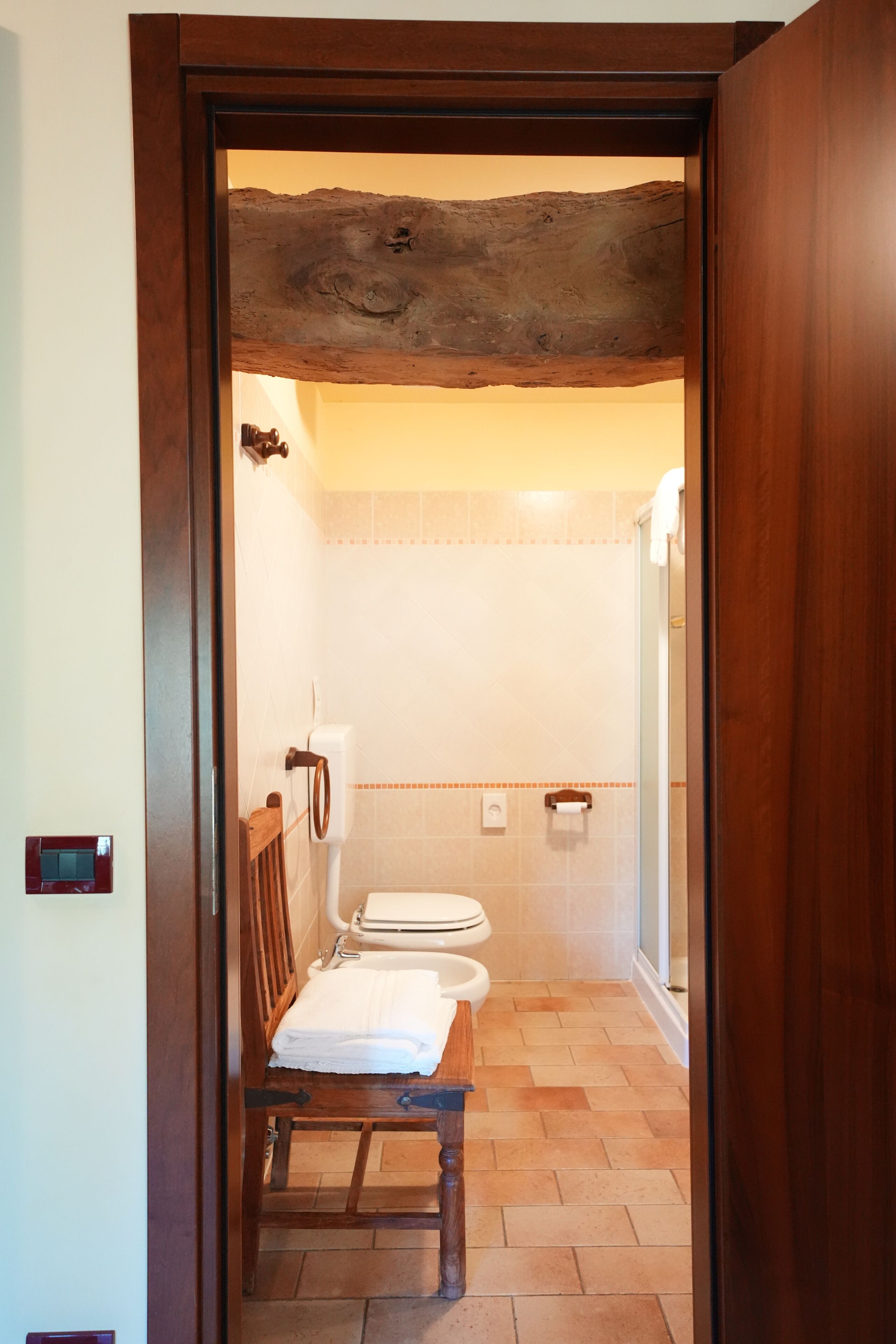 Un baño con un banco de madera, un inodoro y una zona de ducha.
