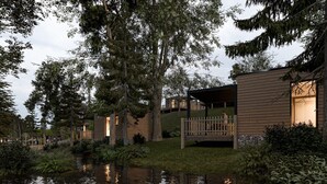 A row of cabins with a wooden deck and a small pond in front.