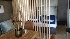 A modern room with a bed, a dining table, a vase with flowers, and a wooden partition.