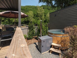 An outdoor deck with a hot tub, seating area, and a sauna unit. - Walsdorf Resort - Sauwer Lodge with Hot Tub | 4p (Luxembourg)