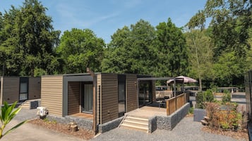 Een rij moderne vakhuizen met houten gevels, een overdekt terras en een grindpad.