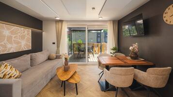 A modern living room with a sofa, a coffee table, and a dining area with chairs and a table.
