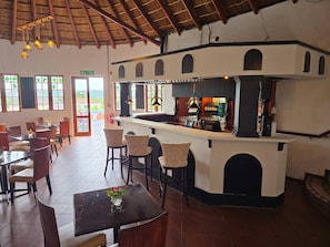 A restaurant with a bar area, multiple tables and chairs, and a view through the windows. - Room-cozy Lodge Room With Garden Views i (Johannesburg)