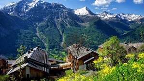 A mountain village with traditional wooden houses, a clear sky, and snow-capped peaks in the background. - 4-guest Studio With Mountain View (Orcieres)
