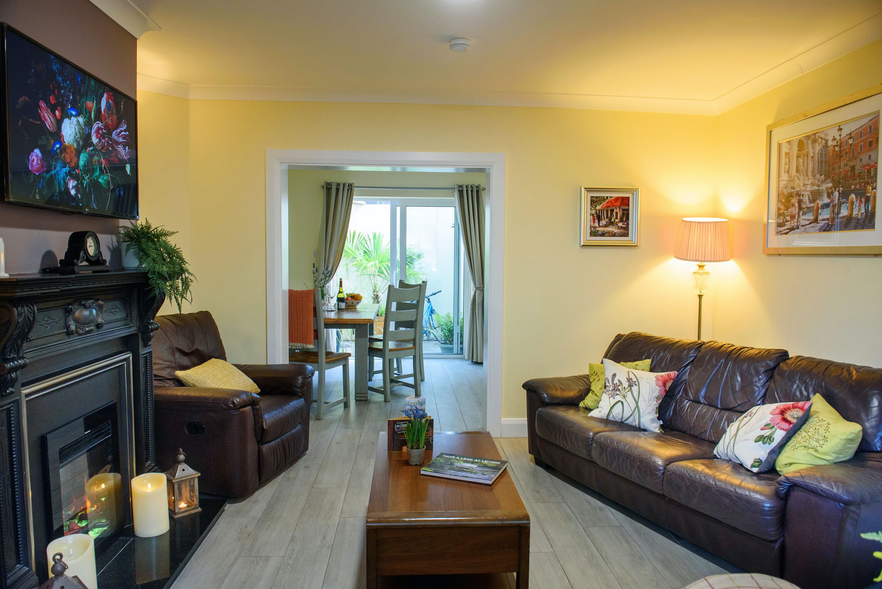 A living room with a fireplace, leather sofas, a coffee table, and a dining area with a table and chairs.