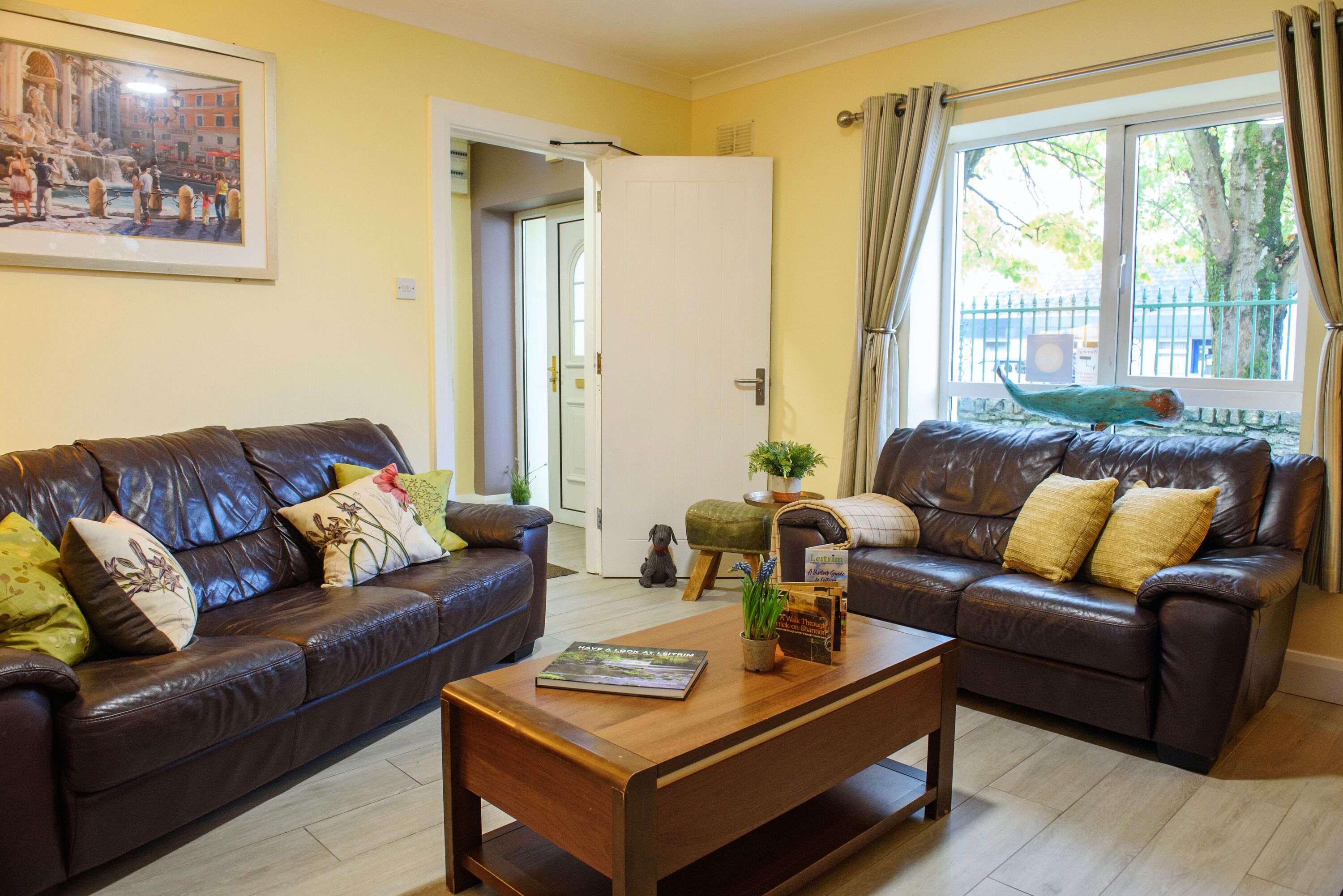 A living room with two brown leather sofas, a wooden coffee table, and a framed picture on the wall.