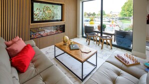 A modern living room with a sofa, a coffee table, a fireplace, and a large window with a view of a parking lot.