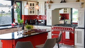 A kitchen with a red island, white cabinets, and a red stove.