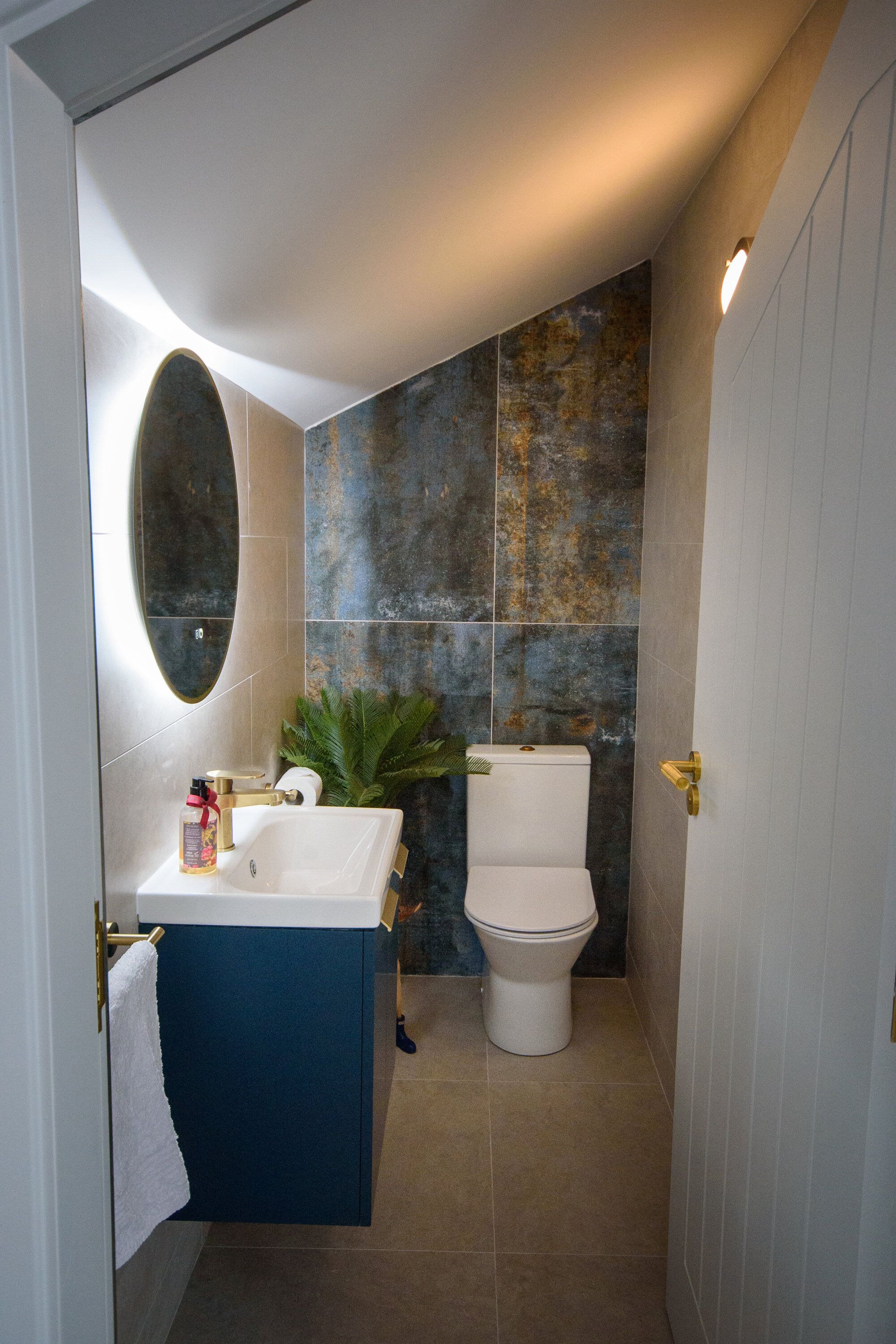 A bathroom with a white sink, blue cabinet, and a toilet against a textured wall.
