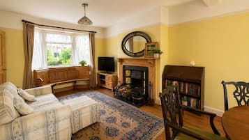 A cozy living room with a sofa, a fireplace, a television, and a bookshelf.